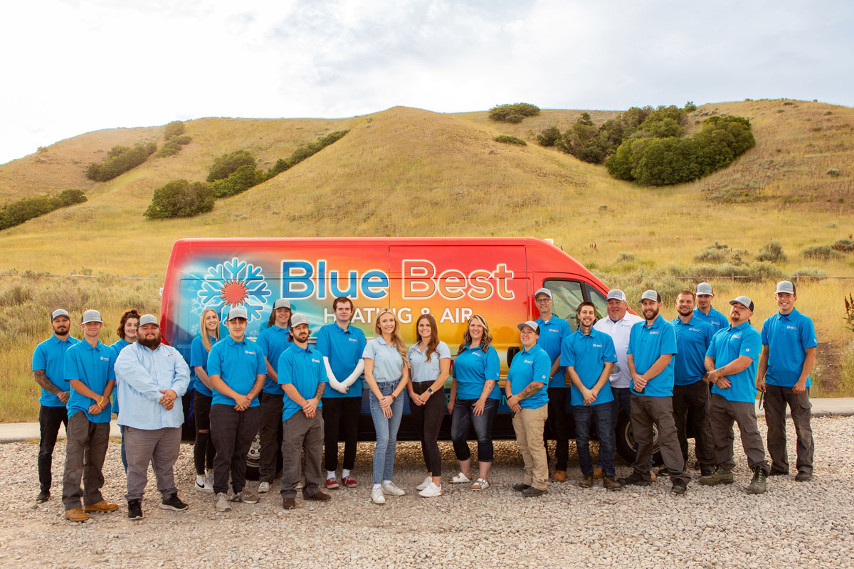 Blue Best Team posing in front of their service vehicle with grassy mountain in the distance