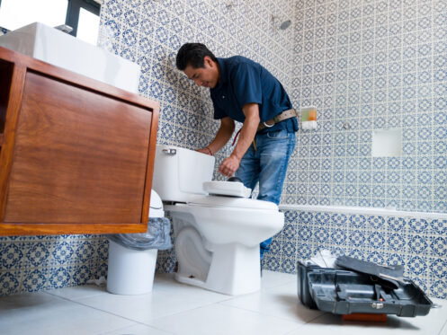 A plumber repairing a toilet